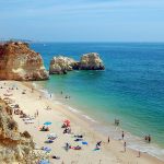 Plage de sable avec des personnes et des falaises