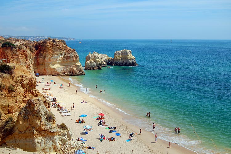 Plage de sable avec des personnes et des falaises