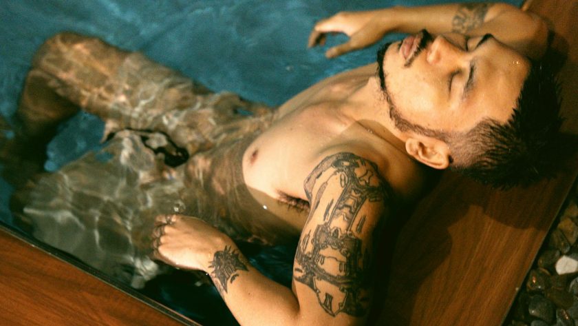 Homme tatoué se relaxant dans l'eau