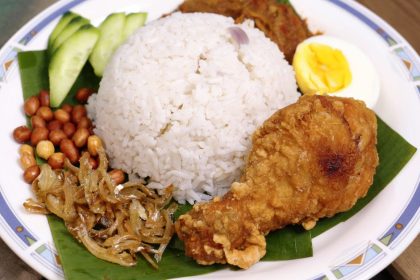 découvrez le nasi lemak, un plat malaisien emblématique à base de riz cuit dans du lait de coco, servi avec des accompagnements savoureux comme des anchois frits, des cacahuètes, des œufs durs et sambal. un voyage culinaire qui éveille vos sens !